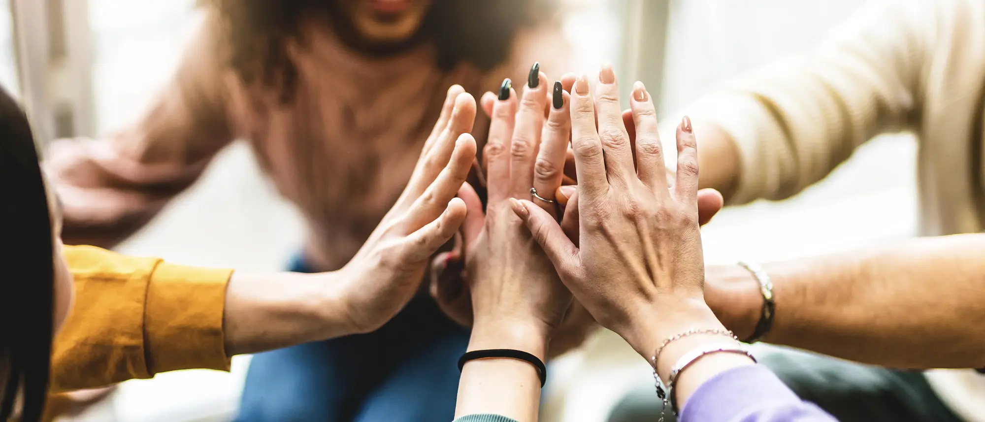 Young multiracial group stacking hands together- Happy diverse friends united at community table having fun- youth Millennial students giving strength motivation- Human resources teamwork concept